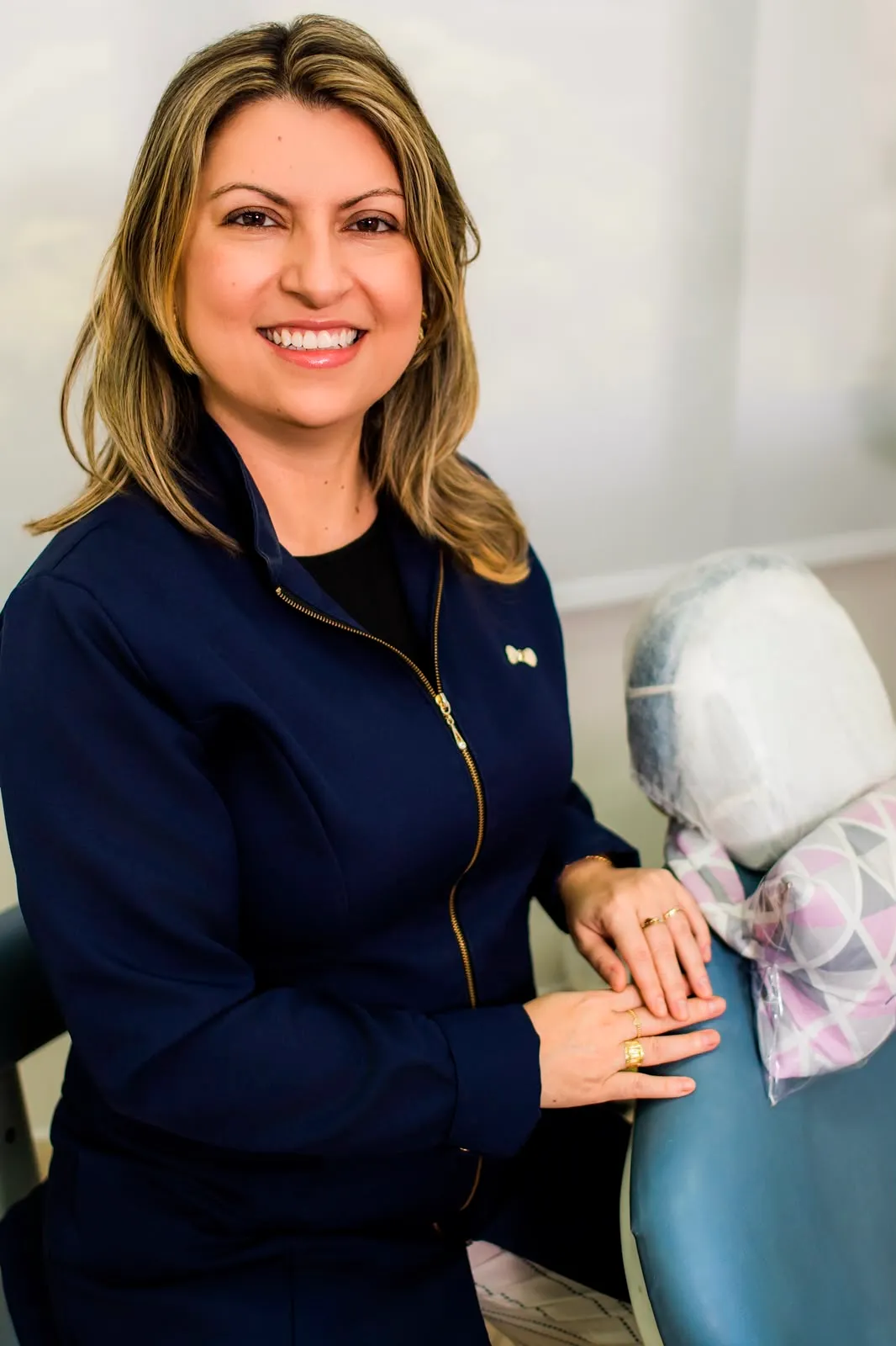 Dra. Sulamita Manhães no consultório, junto à cadeira odontológica